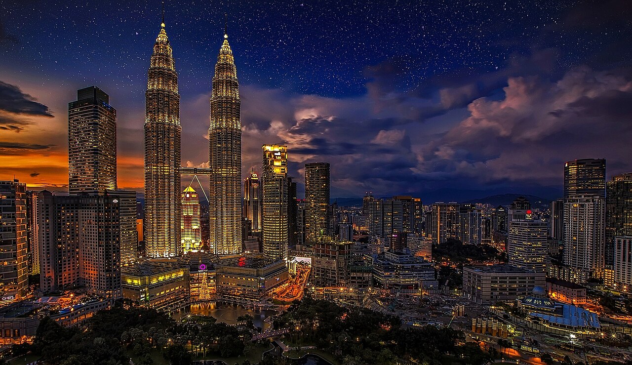 Kuala Lumpur skyline at dusk with the illuminated Petronas Twin Towers under a starry sky
