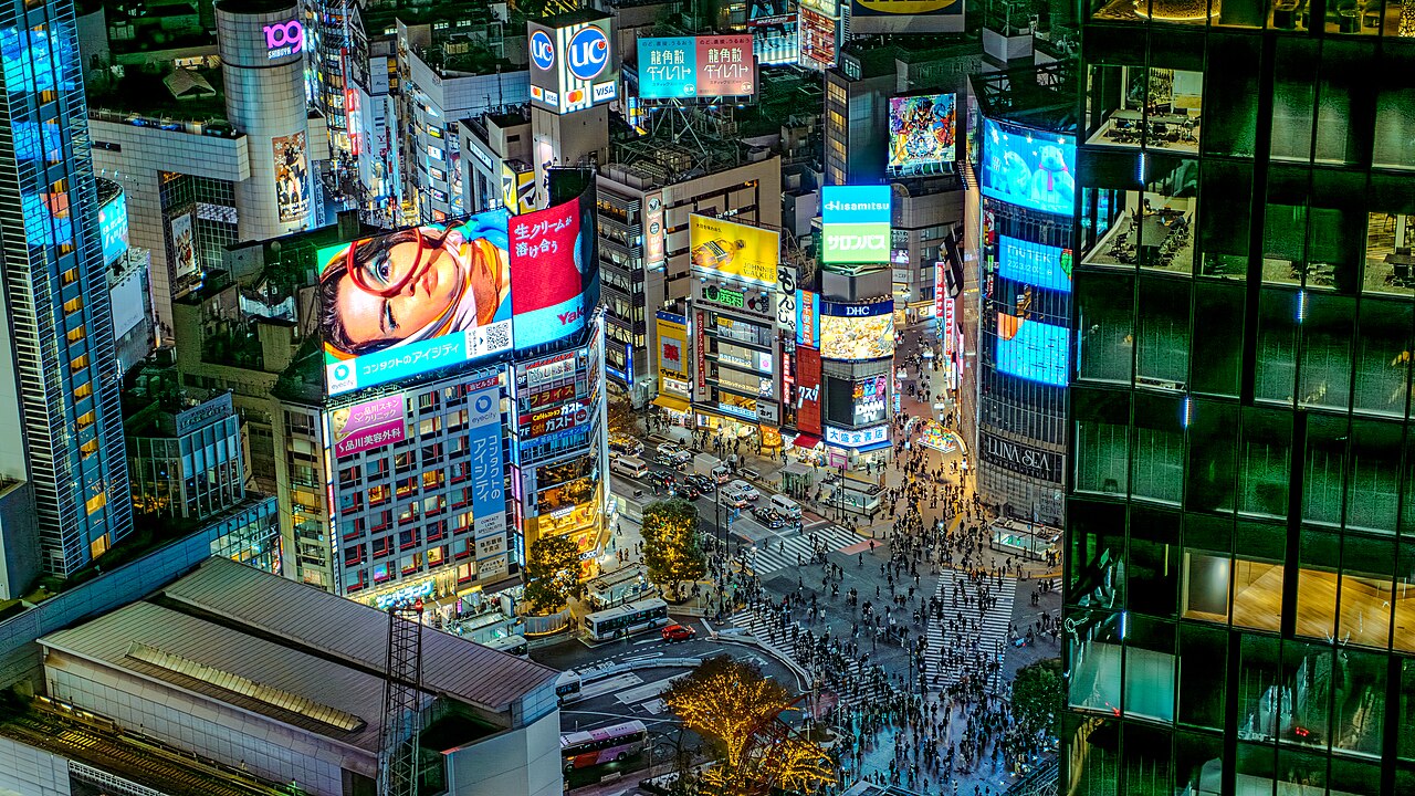 Aerial view of the Shibuya Scramble Crossing in Tokyo, Japan, with crowds of pedestrians crossing in every direction
